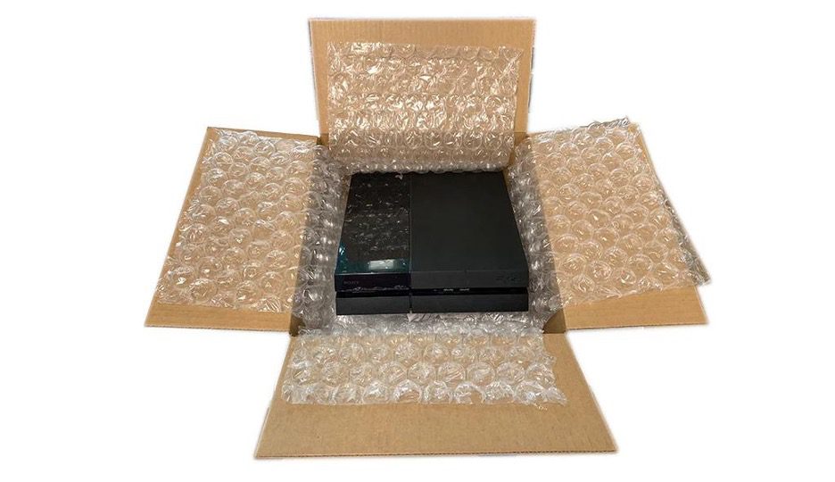 A cardboard box with bubblewrap and a Sony PlayStation 4 inside