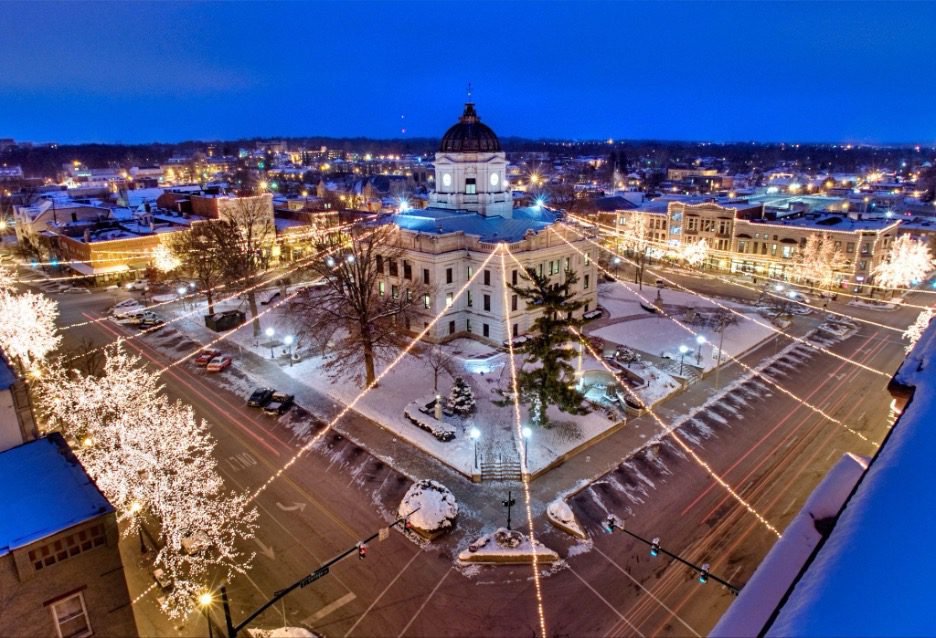 Downtown Bloomington at night featuring the Monroe County Courthouse surrounded by streets lit with the Canopy of Lights and snow-covered sidewalks